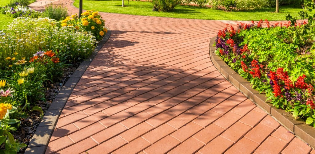 A brick path with blooming landscaping done by Scott's Lawn Care property maintenance services.