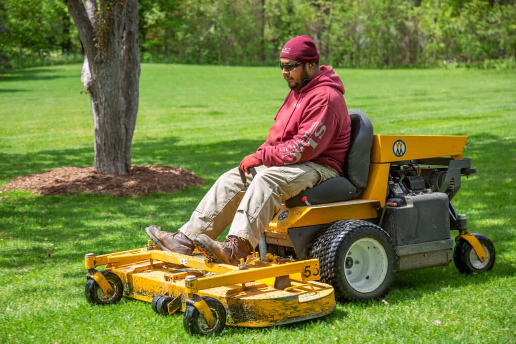 An SLC technician mowing a commercial lawn.