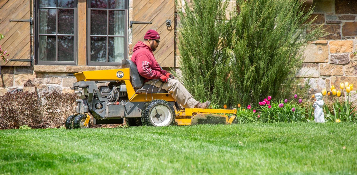 A Scott's Lawn Care Professional mows the lawn with riding lawn mower