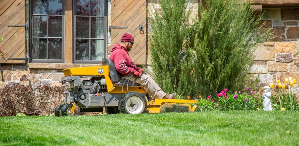 A Scott's Lawn Care Professional mows a lawn with riding lawn mower