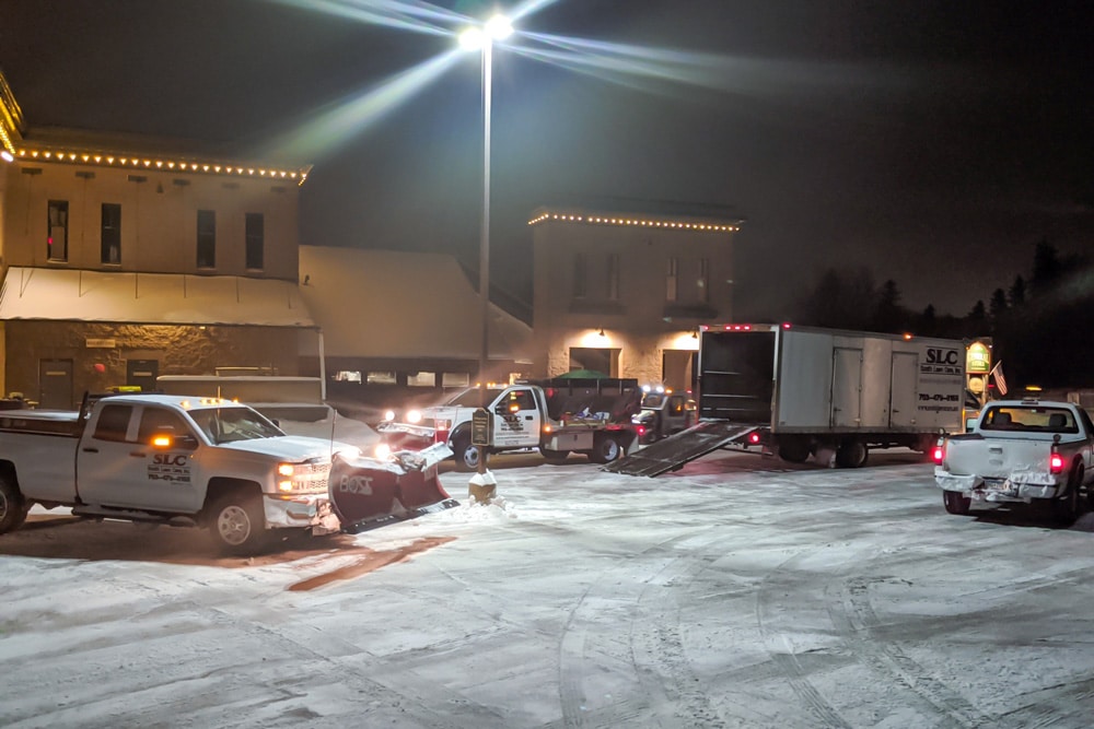 A fleet of trucks and snow removal equipment in front of the General Store of Minnetonka