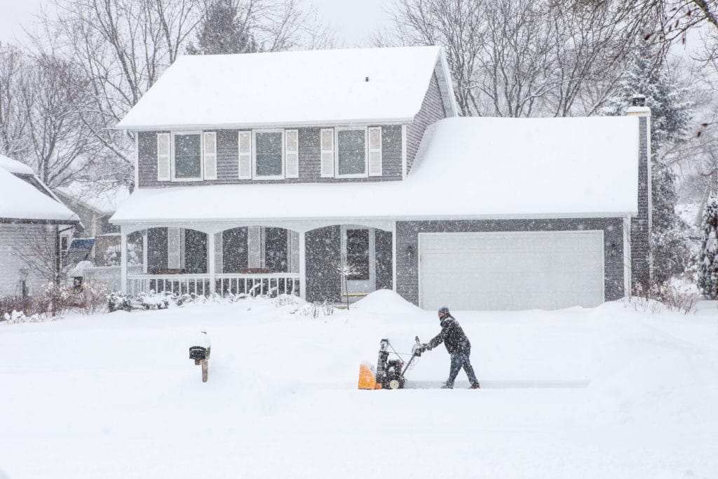 A Scott's Lawn Care Professional snowblowing a driveway during a blizzard