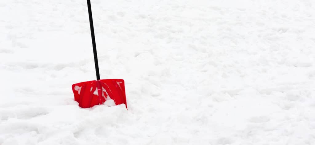 A red shovel stuck in the snow