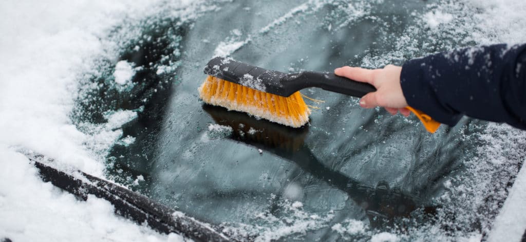 A Scott's Lawn Care professional scrapes ice off a car windshield