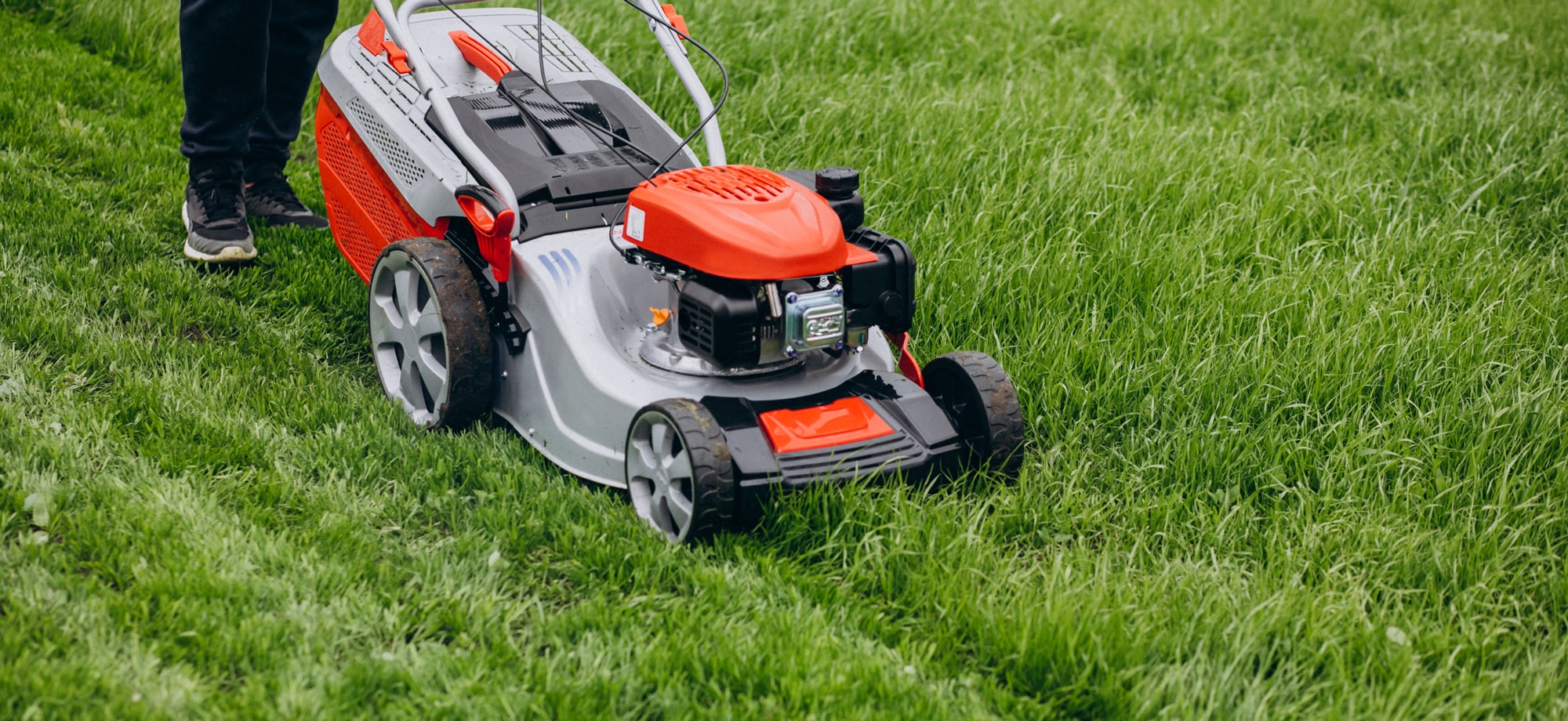 A Scott's Lawn Care professional uses a push mower to trim grass.